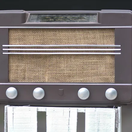 Vintage wooden tabletop radio with a fabric speaker grille and round knobs
