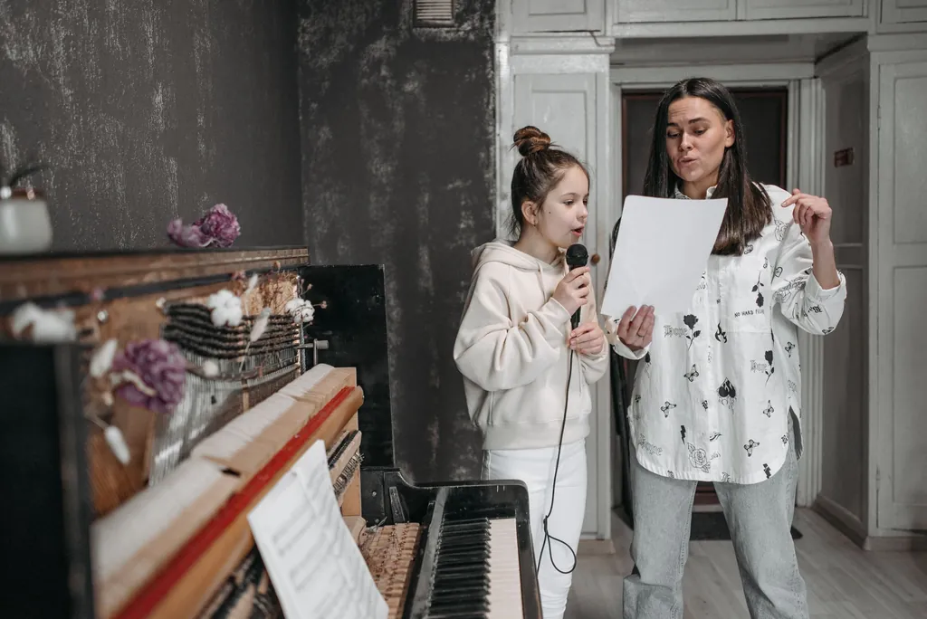 Two singers reading soprano and alto lines from sheet music by a piano