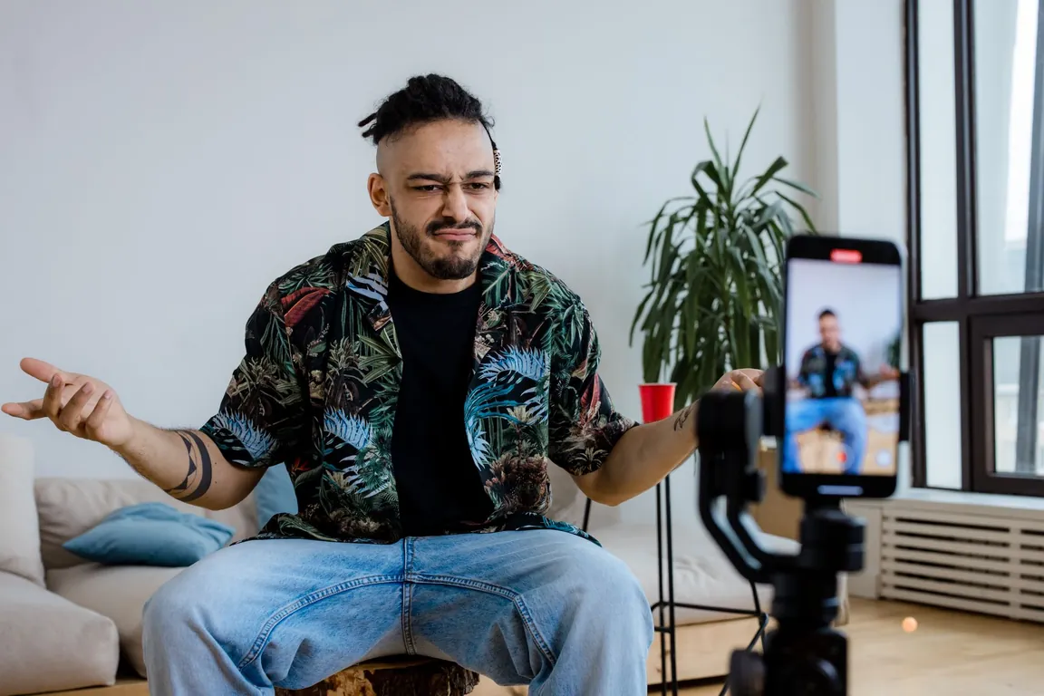 Creator filming himself on a phone tripod while talking to the camera at home