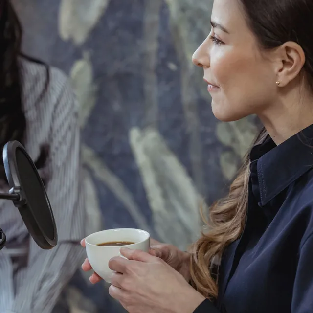 Two women talking at a podcast microphone
