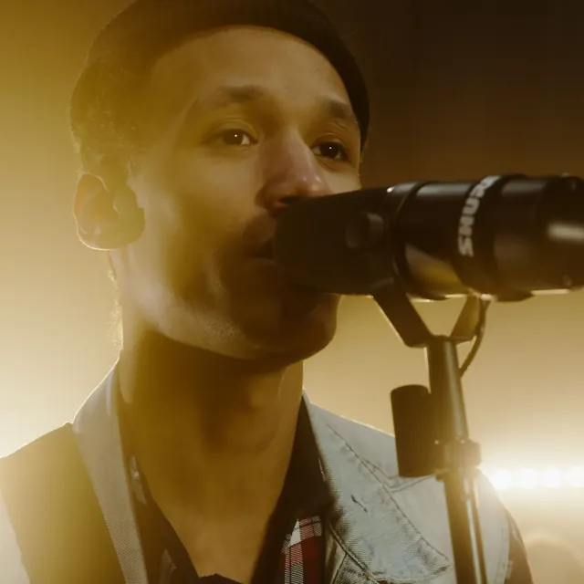 Singer at a microphone in warm golden light