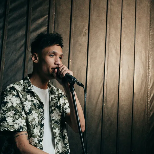 Man speaking into a microphone in a dim, wood-paneled room