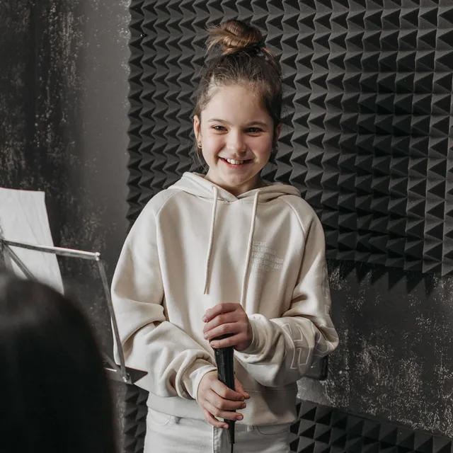 Girl singing into a microphone in a small studio