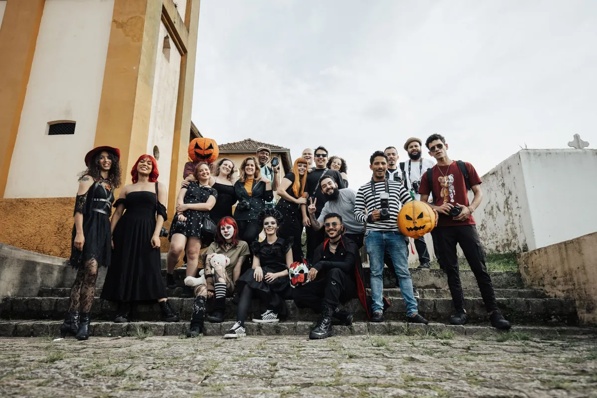 Big group of friends in Halloween costumes posing together on stone steps