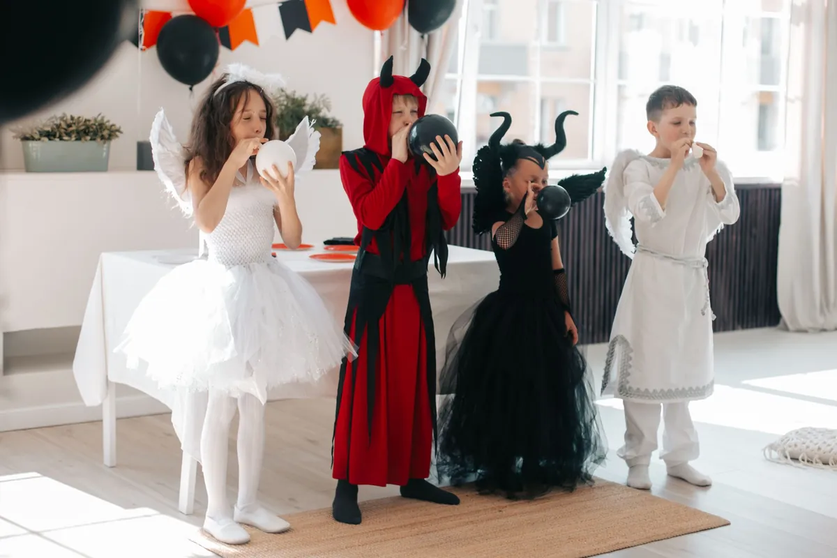 Kids in angel, devil and ghost costumes clowning around at a costume party
