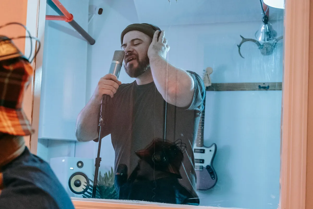 Man in headphones recording vocals in a vocal booth