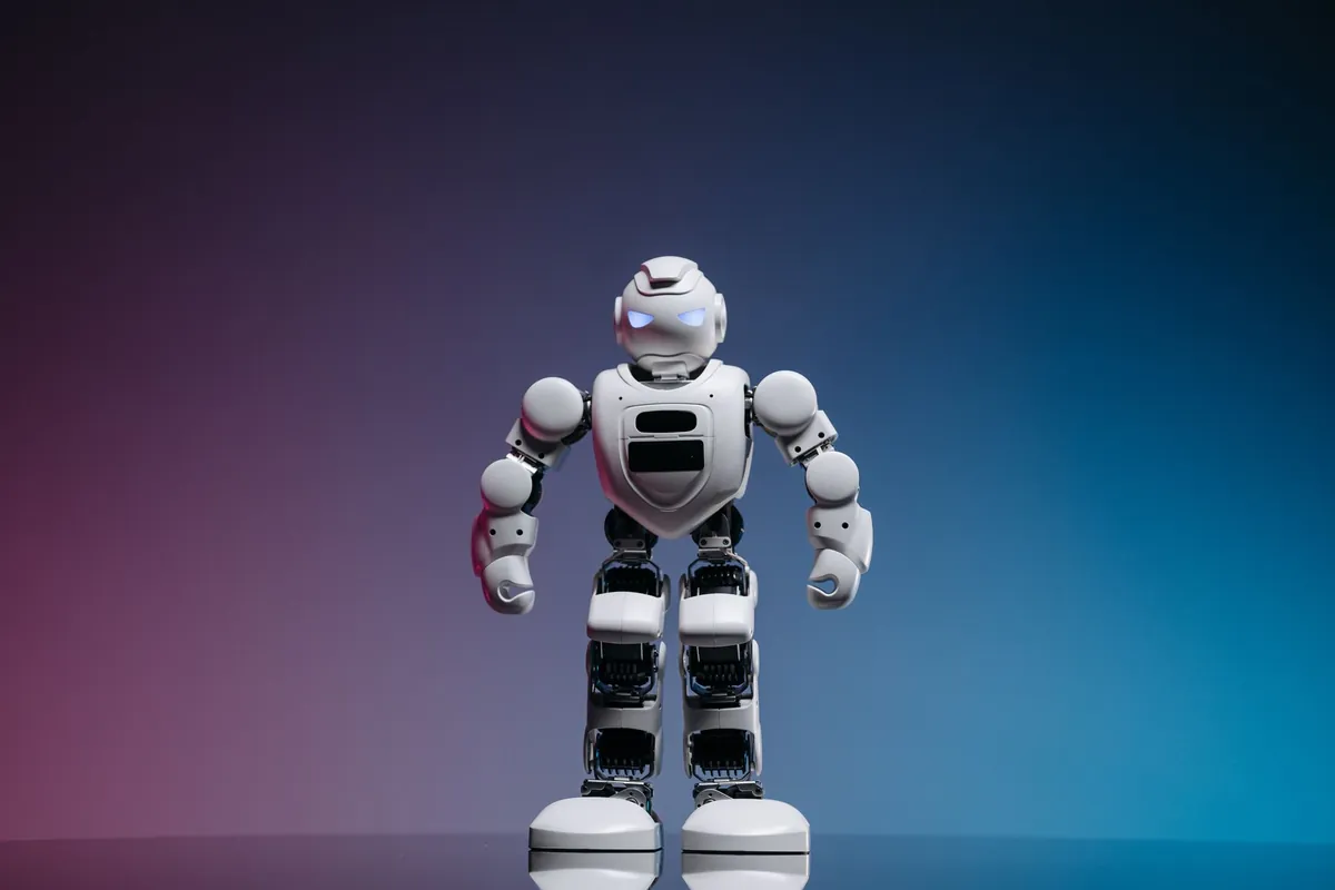Small humanoid robot standing on a purple-blue gradient backdrop