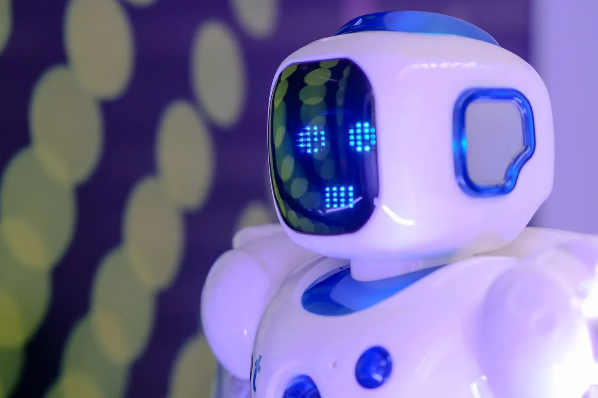 White toy robot with a glowing LED face and big round eyes