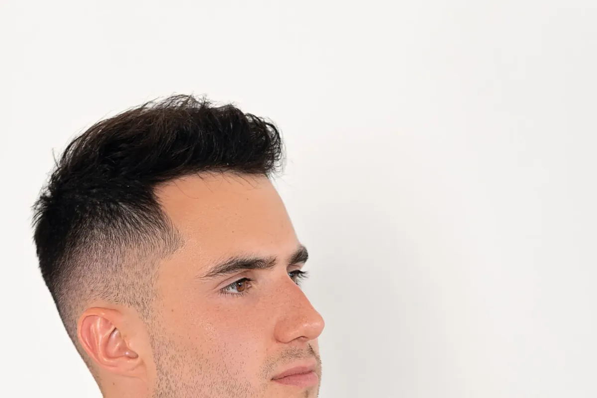 Young man with short dark hair and a bow tie, looking off to the side before he sings