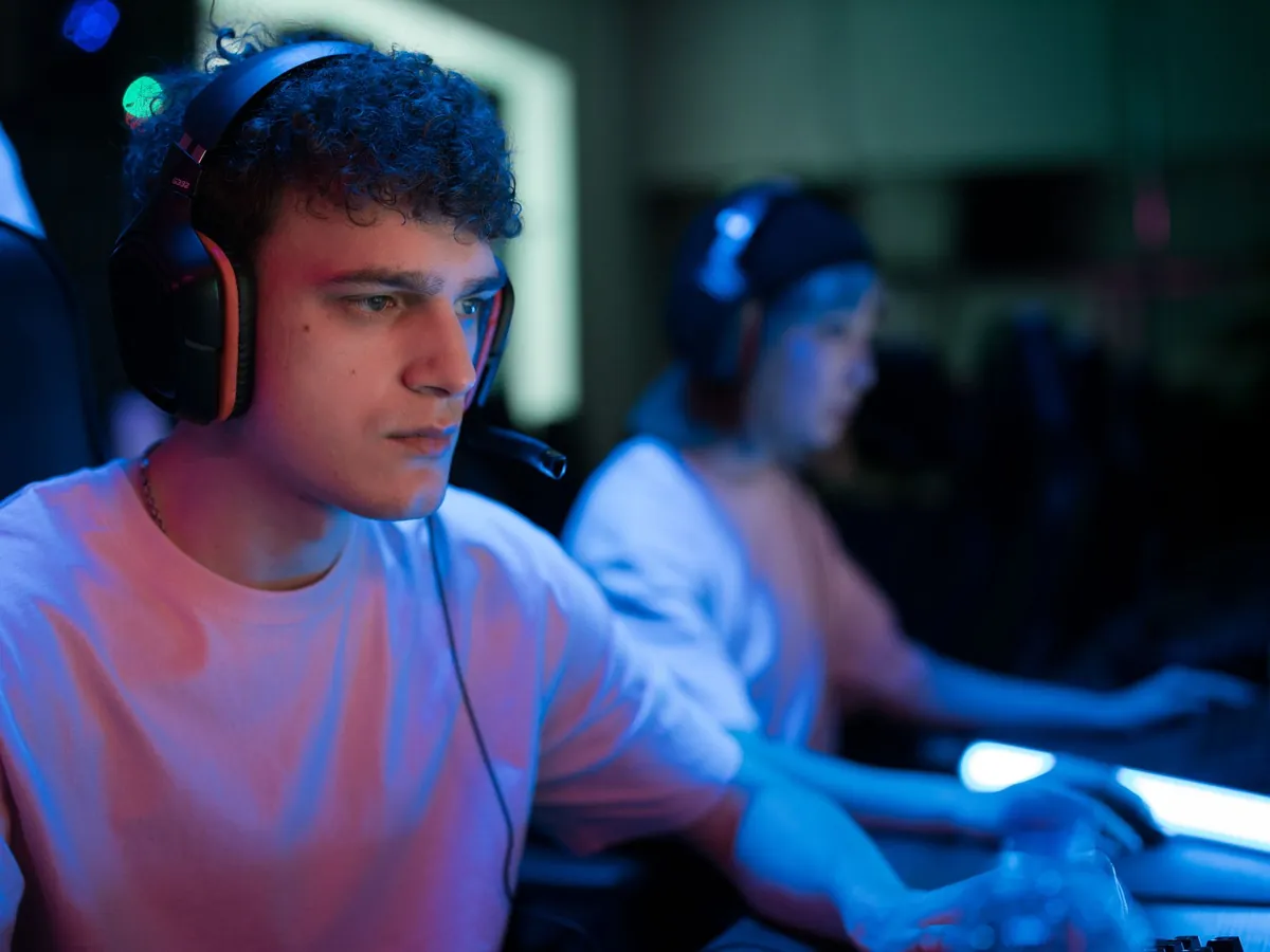 Young gamers in headsets playing together under blue light