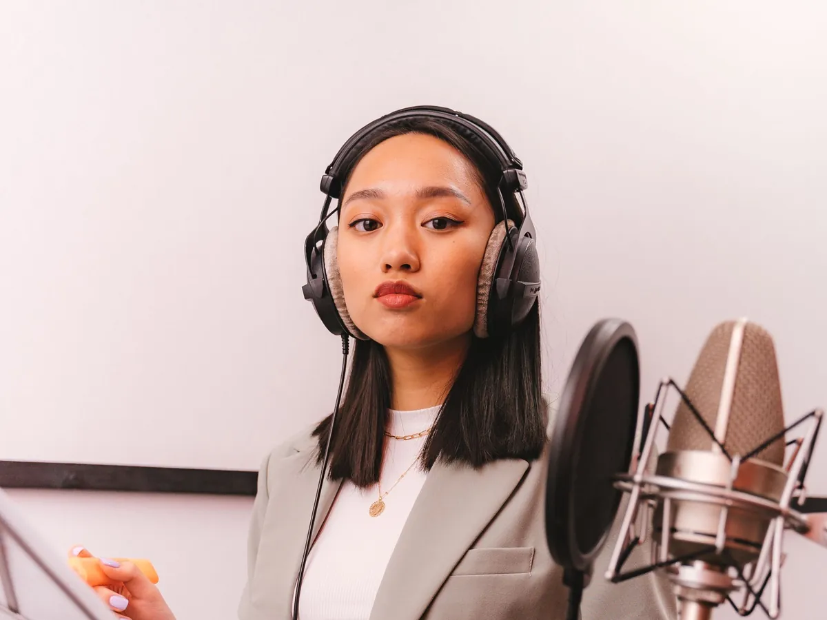Singer in headphones practicing at a studio microphone with a music stand