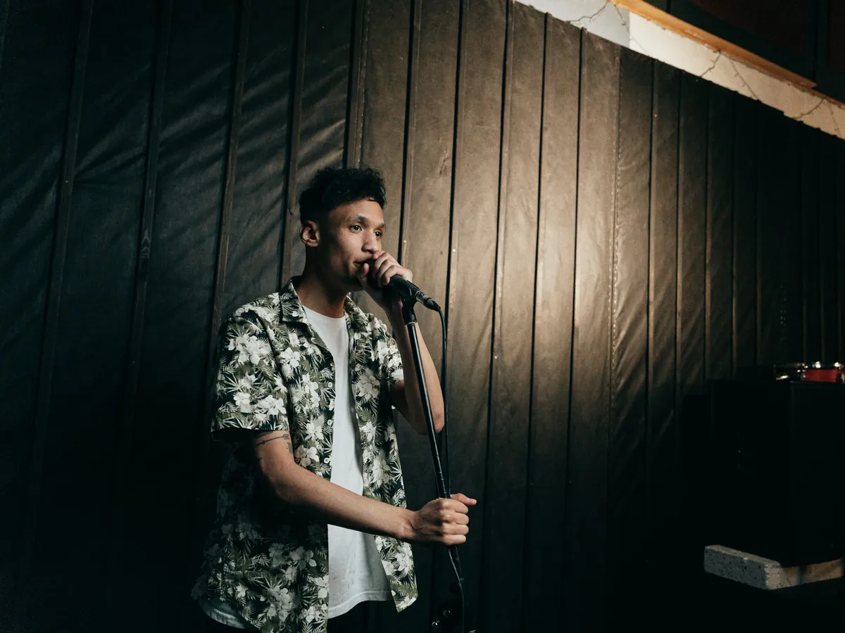 Man speaking into a microphone in a dim room with wooden walls