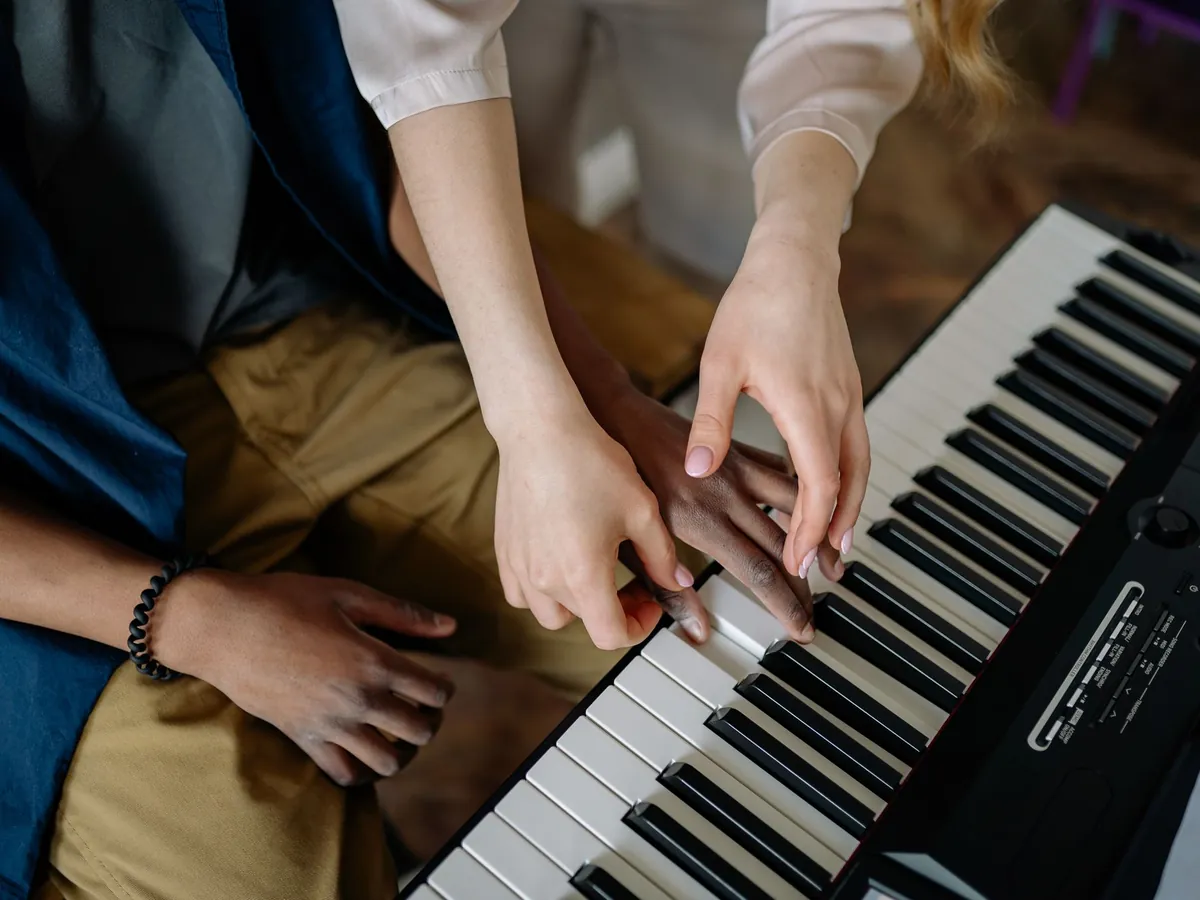 Teacher's hand guiding a student's fingers on a keyboard