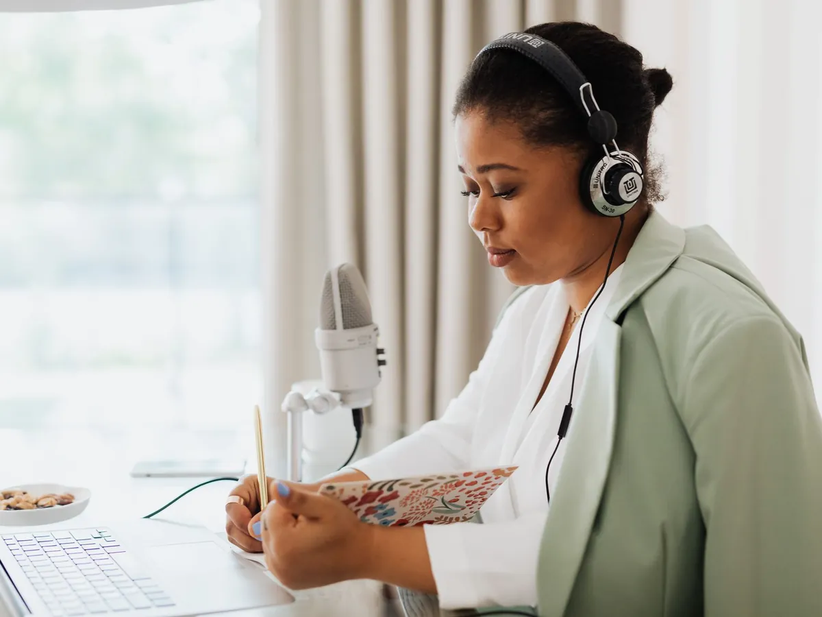 Woman in headphones reading from her notes at a microphone before recording