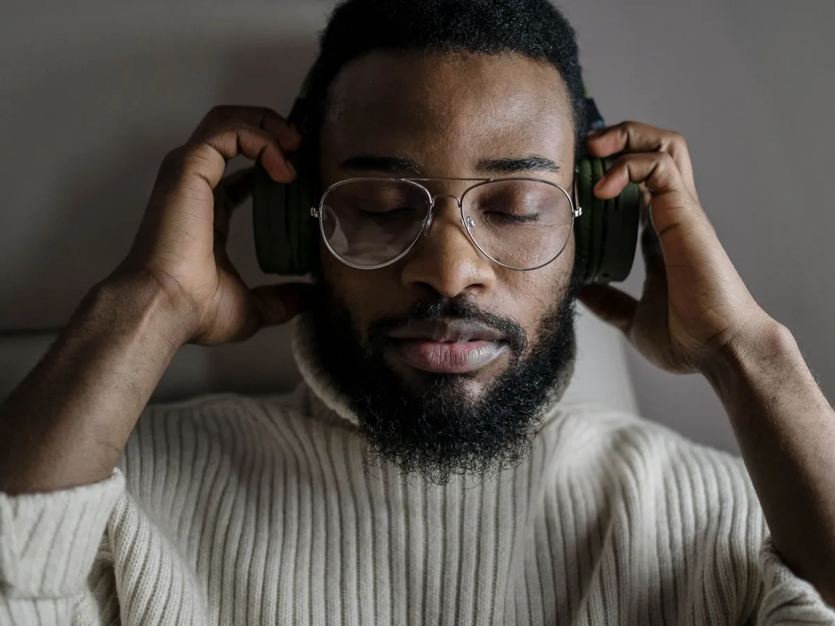 Man in glasses holding his headphones and listening closely