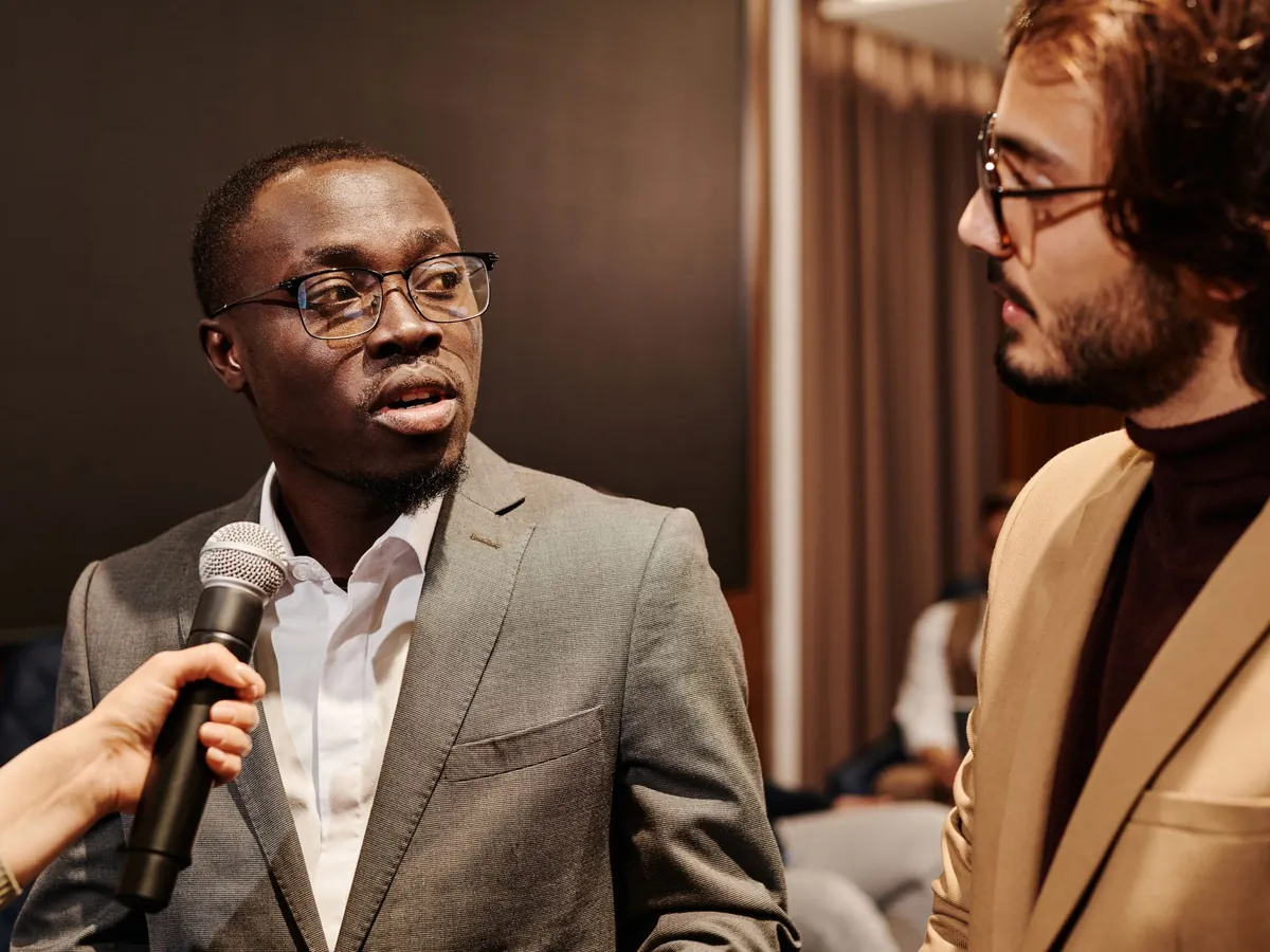 Man in glasses answering a question into a handheld microphone