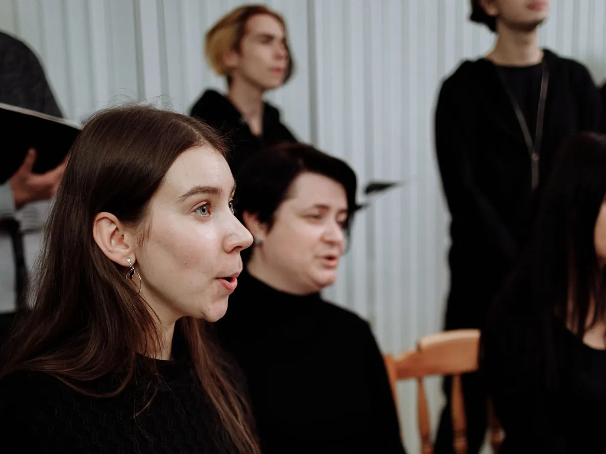 Women in a choir singing their part while holding sheet music