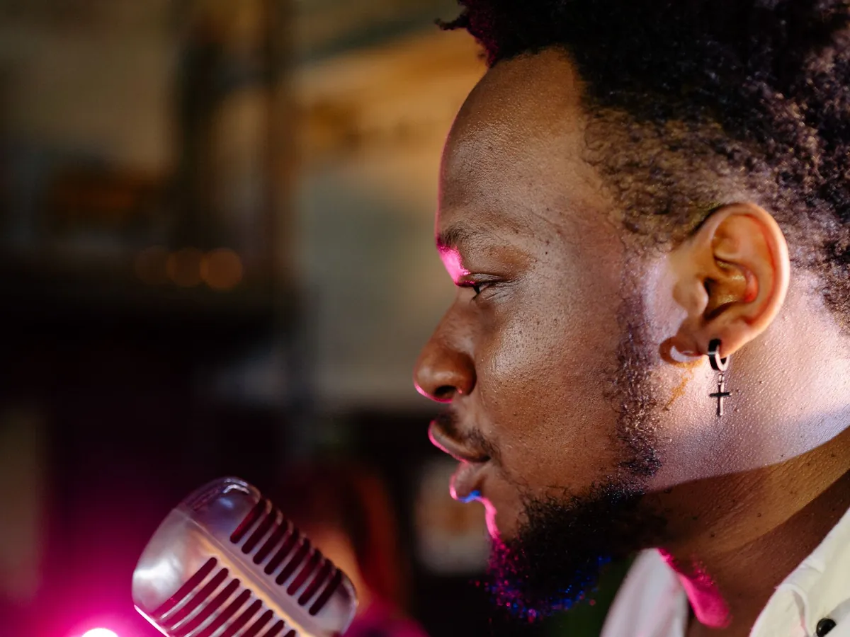 Singer cradling a vintage microphone under warm pink stage light