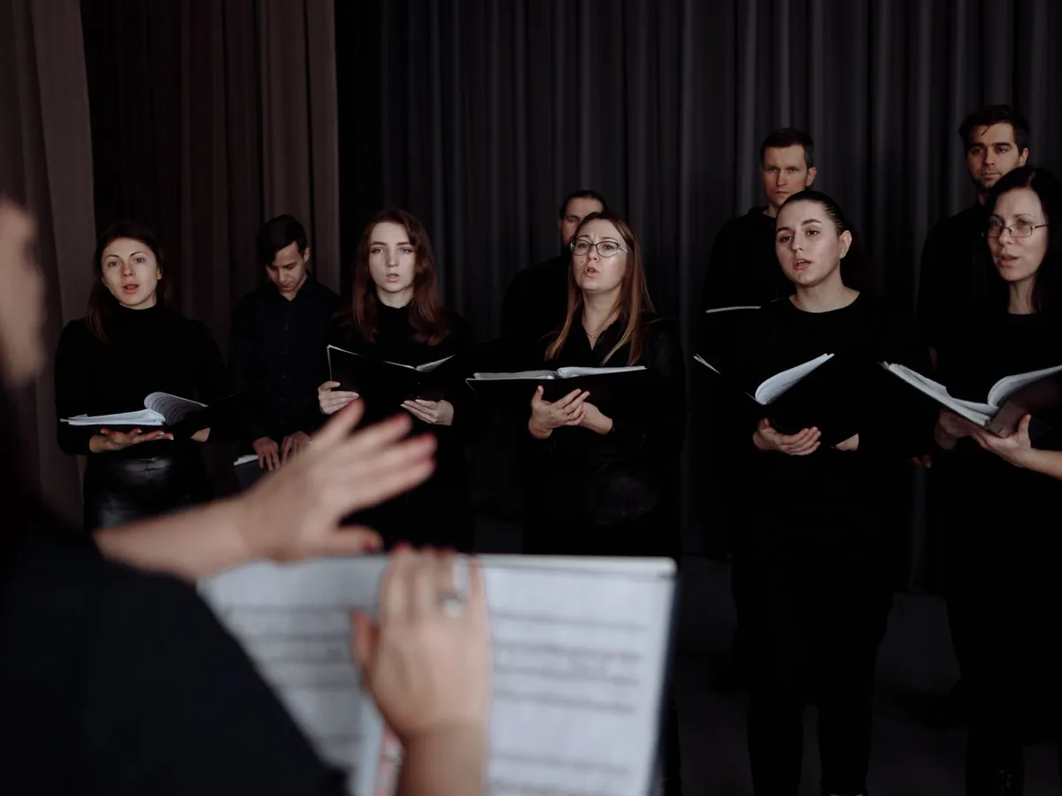 Choir singing in rows while the conductor leads with her hand