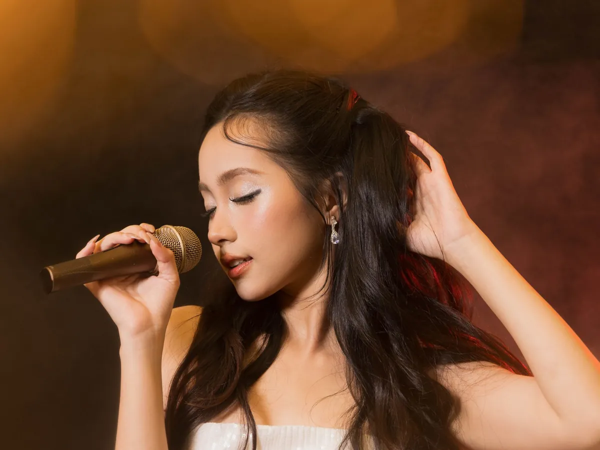 Singer in a satin dress singing into a vintage microphone in warm stage light
