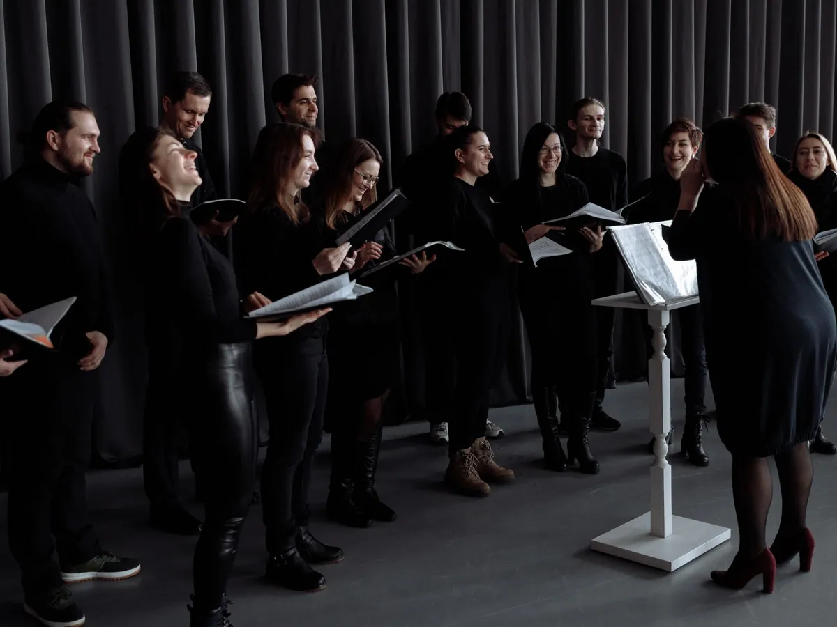 Choir rehearsing in sections around a music stand