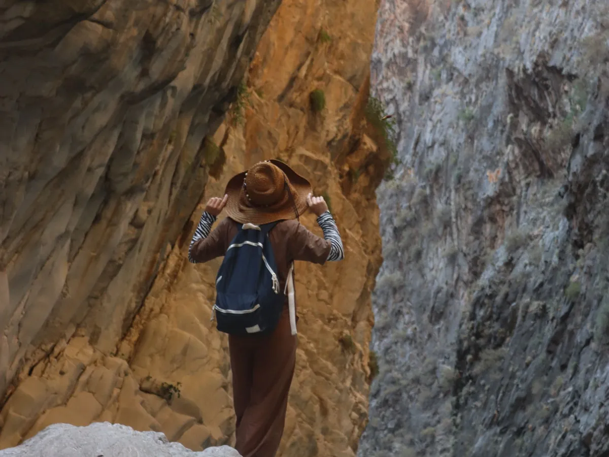 Hiker climbing between the tall rock walls of a narrow canyon