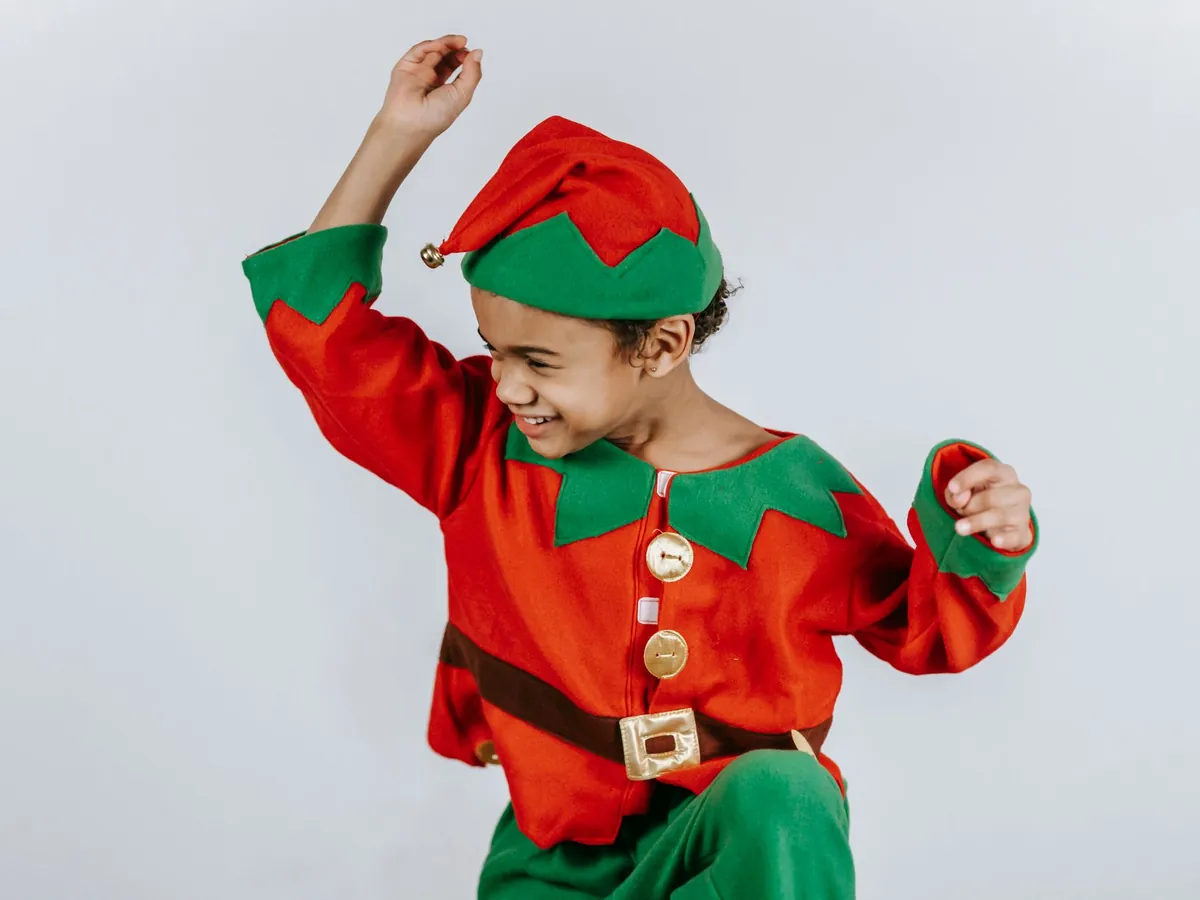 Boy in a Christmas elf costume dancing on a white background