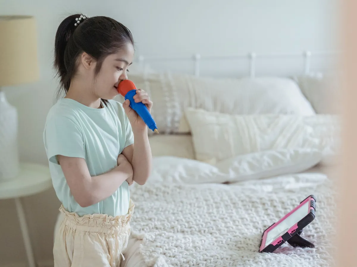 Girl singing into a toy microphone in her bedroom