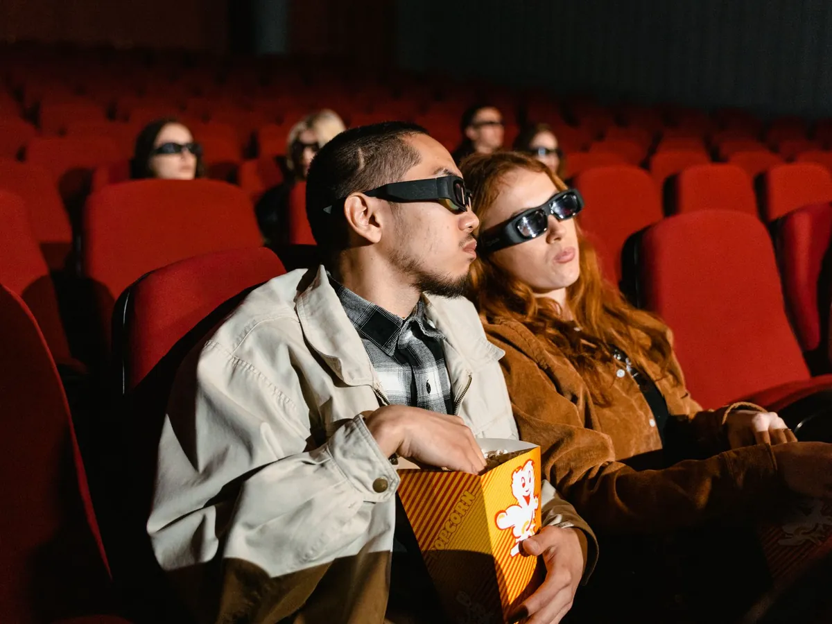 Couple in 3D glasses sharing popcorn in a movie theater